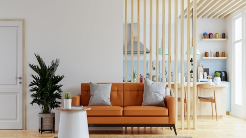 Living room interior wall mockup in warm tones with leather sofa which is behind the kitchen.3d rendering