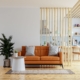 Living room interior wall mockup in warm tones with leather sofa which is behind the kitchen.3d rendering